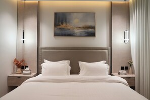 A modern hotel room with a large bed, a painting above the headboard, and bedside tables with lamps. - The Lounge I Luxury 1BR with Private Bar I Almalqa (Riyadh)