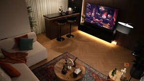 Ett modernt vardagsrum med soffa, soffbord, TV och en barhörna.