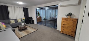 A living room with a sofa, a coffee table, a TV, a dresser, and a sliding glass door leading to a balcony.