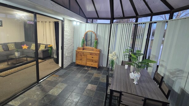 A modern living room with a sofa, a wooden dresser, and a dining table with chairs. - Modern 2BR Home, Sleeps 5,  Parking,  Near Eastgate (Christchurch)