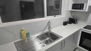 A kitchen with a stainless steel sink, a microwave, a toaster, and a stove. - Modern 2BR Home, Sleeps 5,  Parking,  Near Eastgate (Christchurch)