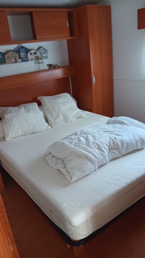 A bed with white bedding, a wooden headboard, and a small shelf above with a model house and number 44. - Loue mobilhome66 m2 3 bedrooms 2 bathrooms 2 wc covered terrace velo..... (Capbreton)