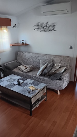 Ein Wohnzimmer mit gestreifter Couch, einem Couchtisch und einem Wandregal mit Dekoration.