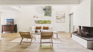 A spacious living room with a white sofa, two wicker chairs, a glass coffee table, and a fireplace. - 600m from beach, superb house for 8 (La Baule-Escoublac)