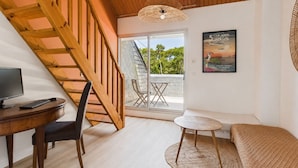 A room with a wooden staircase, a desk with a computer, a sofa, a small round table, and a poster on the wall. - 600m from beach, superb house for 8 (La Baule-Escoublac)