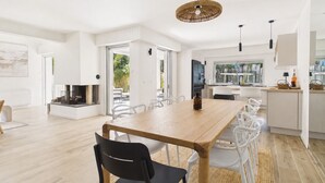 A modern kitchen with white cabinetry, a dining area with a wooden table and chairs, and a large window offering a view of the outdoors. - 600m from beach, superb house for 8 (La Baule-Escoublac)