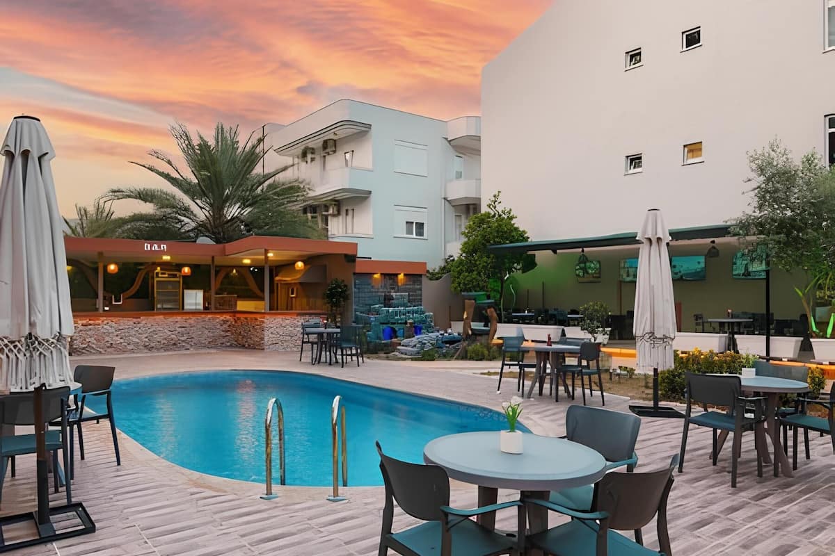 A poolside area with a pool, outdoor seating, and a building with multiple windows.