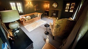 Uma sala de estar aconchegante com sofá, luminária, lareira e poltrona estampada.