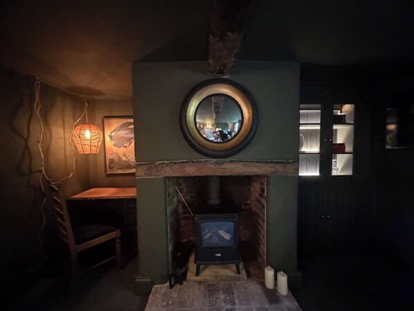 A cozy room with a fireplace, a round mirror above it, and a wooden table.