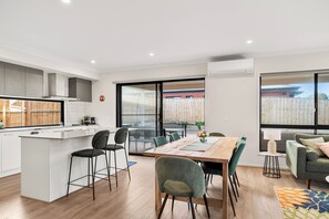 A modern kitchen with a central island, dining area with chairs, and a sofa. - Family holiday at Pembrey Loop Cowes (Cowes)