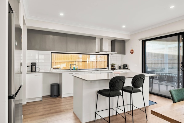 A modern kitchen with white cabinetry, a central island, and two bar stools. - Family holiday at Pembrey Loop Cowes (Cowes)