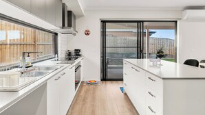 Et moderne køkken med en central ø, en skydedør til en baghave og en indbygget ovn.