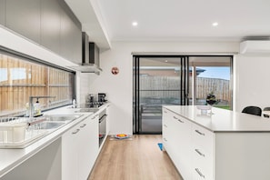 A modern kitchen with a central island, a sliding glass door to a backyard, and a built-in oven. - Family holiday at Pembrey Loop Cowes (Cowes)