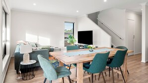 En moderne stue med spiseområde, trappe og et stort vindue.