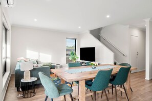 A modern living room with a dining area, a staircase, and a large window. - Family holiday at Pembrey Loop Cowes (Cowes)