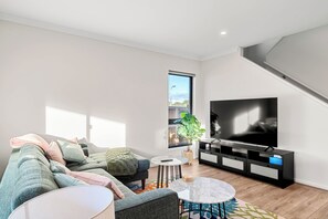 A modern living room with a sectional sofa, a flat-screen TV, a small round table, and a potted plant. - Family holiday at Pembrey Loop Cowes (Cowes)