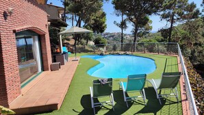 A swimming pool with a patio area, a brick house, and a view of the surrounding landscape. - Beautiful villa with all comforts, peace and quiet (Lloret de Mar)