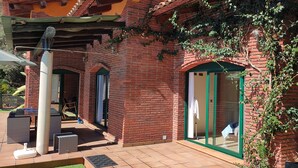 A brick building with a patio area, outdoor seating, and a covered section. - Beautiful villa with all comforts, peace and quiet (Lloret de Mar)