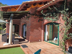 A brick building with a patio area, outdoor seating, and a covered section. - Beautiful villa with all comforts, peace and quiet (Lloret de Mar)