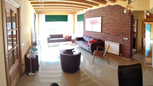 A spacious living area with a brick wall, a sofa, a coffee table, and a fan. - Beautiful villa with all comforts, peace and quiet (Lloret de Mar)