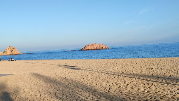 A beach with clear skies, a sandy shore, and a few people. - Beautiful villa with all comforts, peace and quiet (Lloret de Mar)