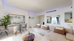 Ein modernes Wohnzimmer mit einer Couch, einem Esstisch, Stühlen und einem großen Spiegel.