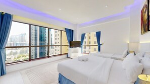 Ein Hotelzimmer mit großem Fenster, zwei Betten, einem Flachbildfernseher und einem Bild an der Wand.