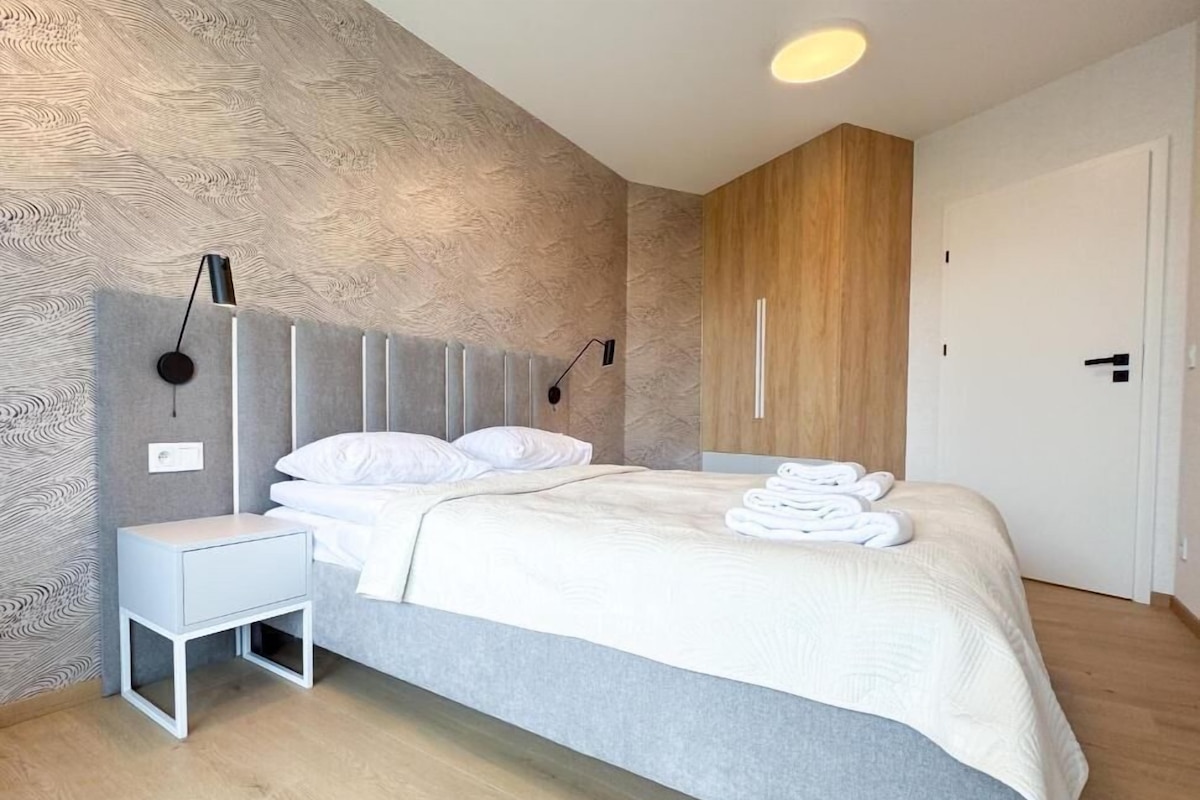 Una camera da letto moderna con un letto, comodini e una parete d'accento in legno.