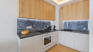 Una cucina moderna con zoccolo in marmo, mobili in legno e forno integrato.