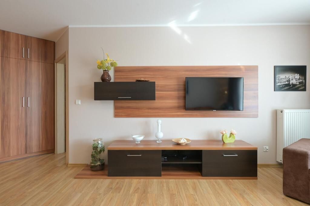 Una sala de estar moderna con un televisor montado en un panel de madera, un mueble empotrado con cajones y un radiador en la pared.