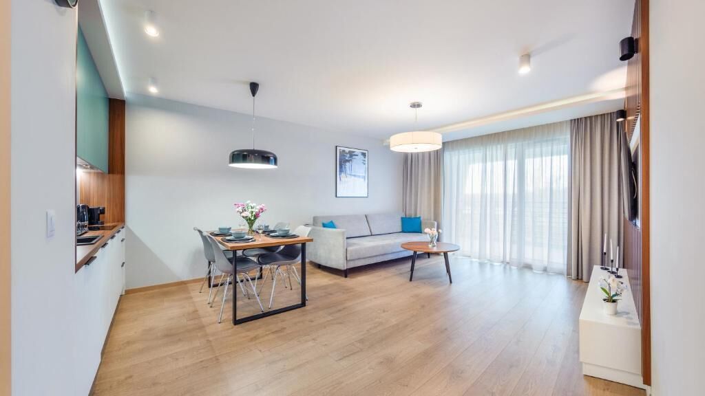 Una sala de estar moderna con un sofá, una mesa de comedor y una zona de cocina con cafetera.