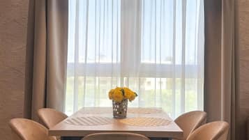 A dining area with a table, chairs, a vase with yellow flowers, and a hanging light fixture.