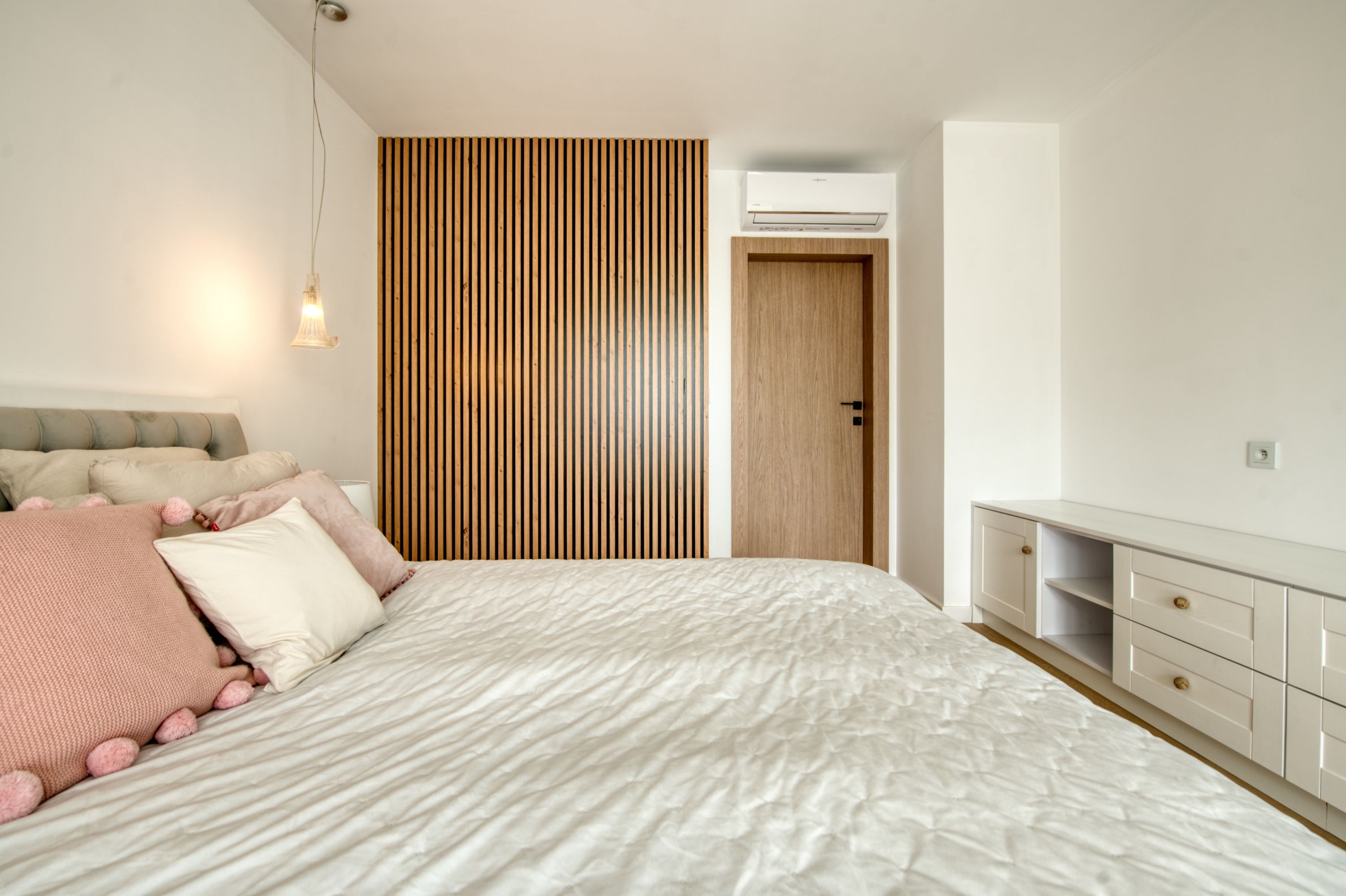 Un dormitorio con cama, armario, puerta y equipo de aire acondicionado.