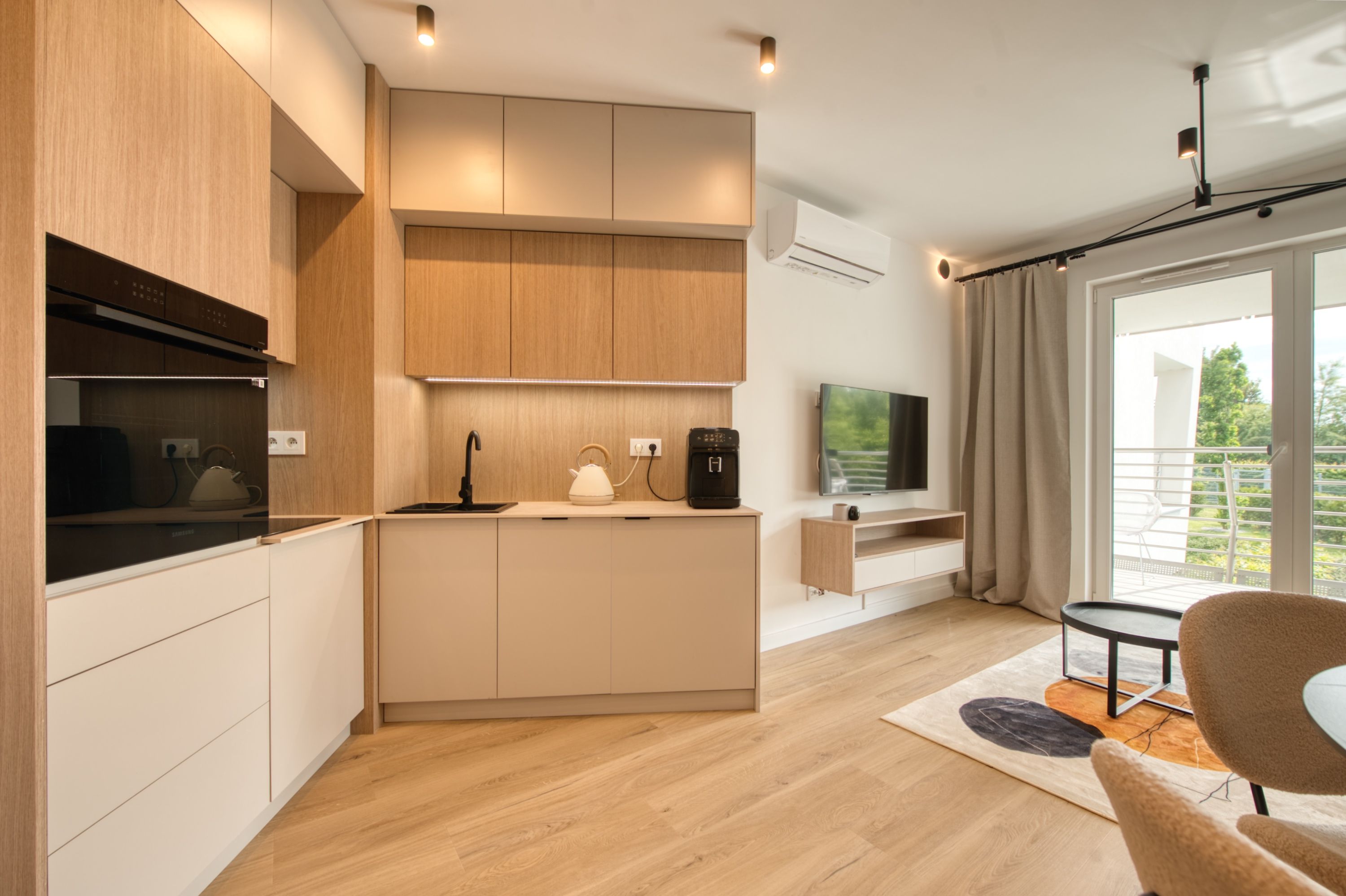 A modern kitchen with a built-in stove, kettle, and coffee maker.
