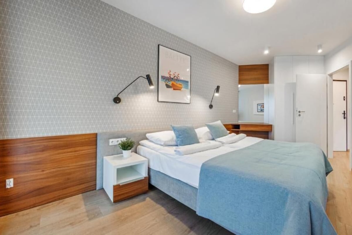 Camera da letto moderna con un letto, comodini, abat-jour e una porta.