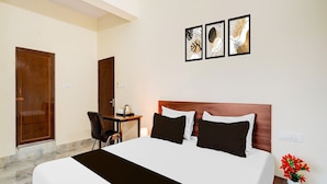 Una habitación de hotel con cama, escritorio, silla y una obra de arte en la pared.
