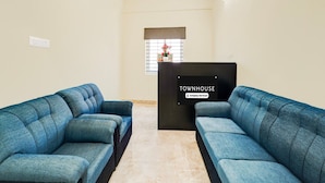 Un área de recepción con dos sofás azules, un mostrador negro y una ventana con persianas.