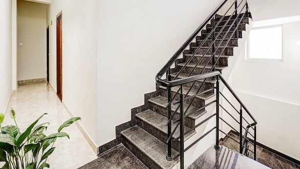Una escalera moderna con barandilla de metal que conduce a un rellano con ventana.