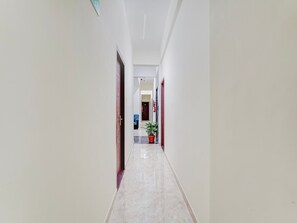 A corridor with white walls, a marble floor, and a door at the end. - Deluxe Hennur Prakruthi Layout Bangalore (Bengaluru)