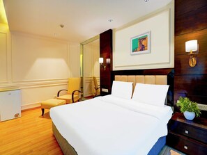 Une chambre d’hôtel avec un grand lit, un bureau, une chaise, un miroir et un tableau au mur.