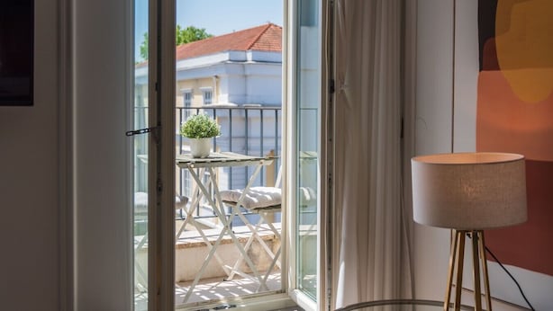 Een balkon met een bloempot, een tafeltje en een lamp.