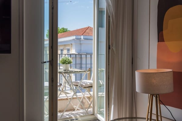 Ein Balkon mit einem Blumentopf, einem kleinen Tisch und einer Lampe.