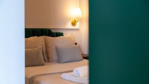 Een hotelkamer met een bed, kussens, een nachtkastje en een wandlamp.