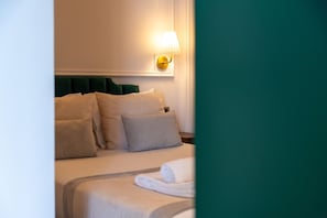 Ein Hotelzimmer mit Bett, Kissen, Nachttisch und einer Wandlampe.