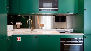 Een keuken met groene kastjes, een Siemens magnetron, een spoelbak, een fornuis en een vaatwasser.