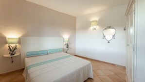 Une chambre à coucher avec un lit, des lampes de chevet, un miroir fixé au mur et une porte.