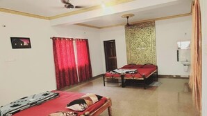 A room with two beds, a ceiling fan, a water dispenser, and a red curtain. - Coorg Silent Stay - Homestay (Madikeri)