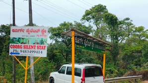 A sign for Coorg Silent Stay with contact information and a directional arrow. - Coorg Silent Stay - Homestay (Madikeri)
