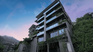 Un hotel de varios pisos con balcones, fachada de piedra y abundante vegetación.