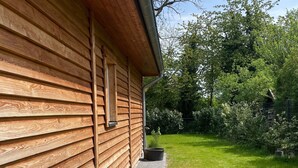 A wooden building with a brick pathway leading to a grassy yard. - Holiday Home 'Strand Haus' with Private Terrace, Private Garden and Wi-Fi (Elsfleth)